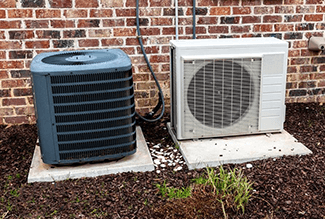 Side-by-side look at a standard, whole-house AC unit (left) and a ductless A/C mini split outside unit (right)